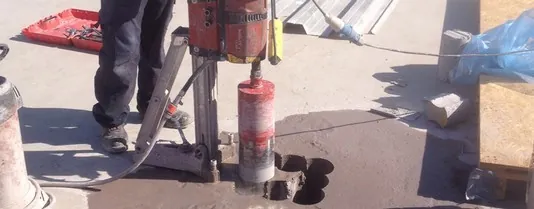 Técnico de PRP perforando una losa con taladro de corona de diamante